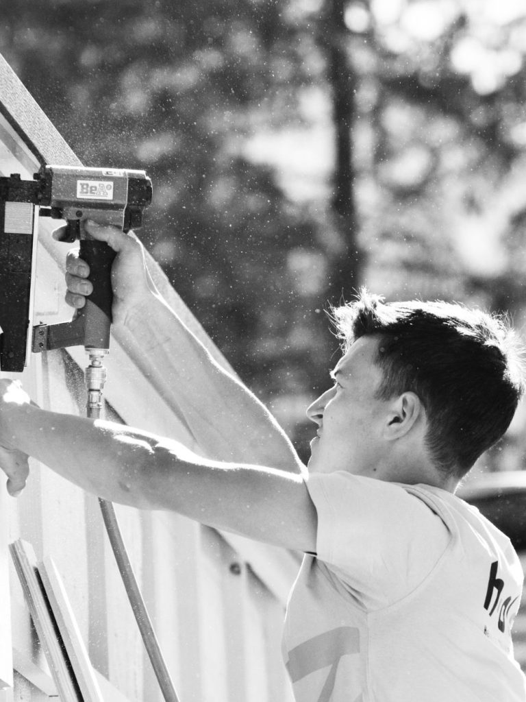 Niklas Niklas mit Akkuschrauber am Büro Container von Heinrich Olivier Zimmerei in Au, Bregenzerwald, spezialisiert auf Holzbau